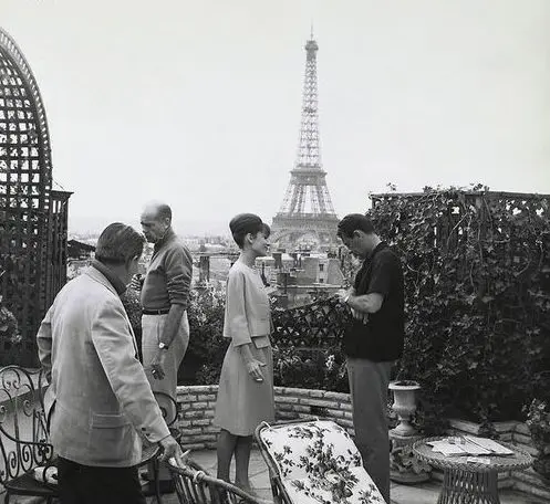 Audrey Hepburn at Hotel Raphael in Paris with her film crew, capturing a classic moment of Hollywood elegance in a luxurious Parisian setting.