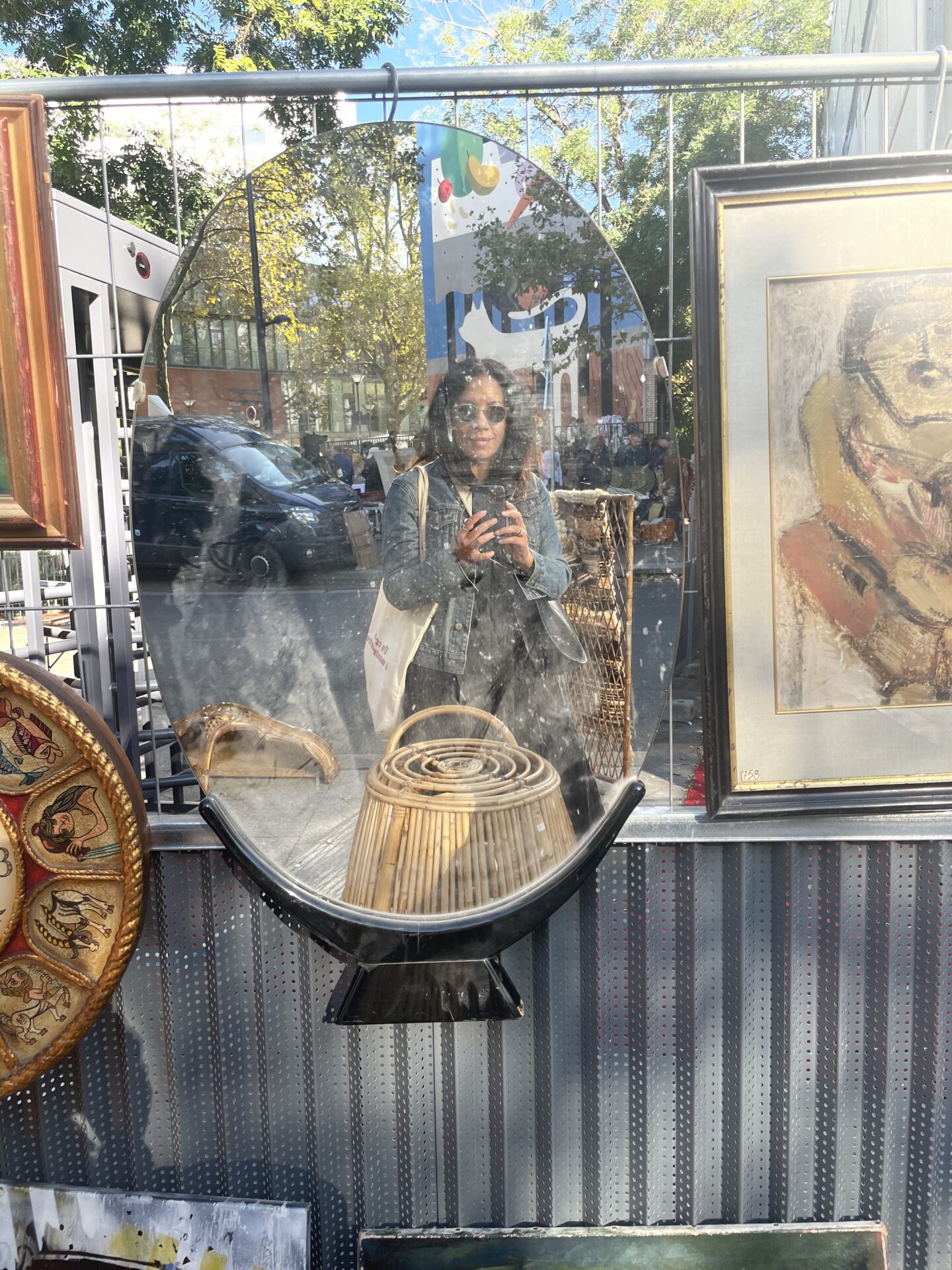 Author surrounded by charming antiques and bustling activity at Puces de Vanves Flea Market, September 2023. The photo captures the vibrant atmosphere of the market with people shopping and working among vintage items, illustrating a lively and nostalgic scene.