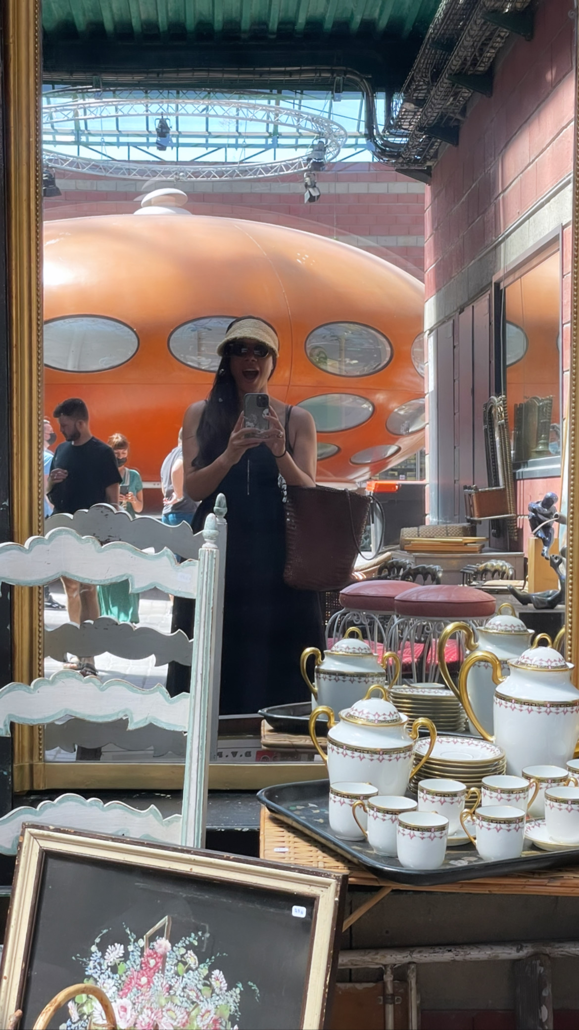 Spaceship anyone? Me smiling at the Puces de Saint-Ouen flea market in Paris, France, 2021, surrounded by vintage treasures and eclectic finds, embodying the charm of Parisian thrift culture.