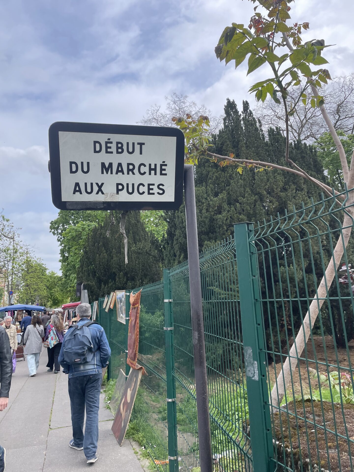 Charming outdoor sign marking the start of the Paris Puces de Vanves Flea Market, with shoppers milling about and basking in the vibrant, eclectic vibe of vintage treasure hunting.