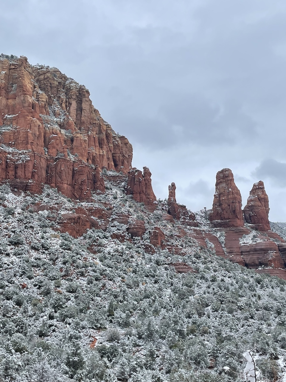 Stunning view of Sedona's red rock formations blanketed in fresh snow, peeking through the white landscape, creating an otherworldly atmosphere. This beautiful scene symbolizes the wonders of America and the importance of learning to coexist in peace.