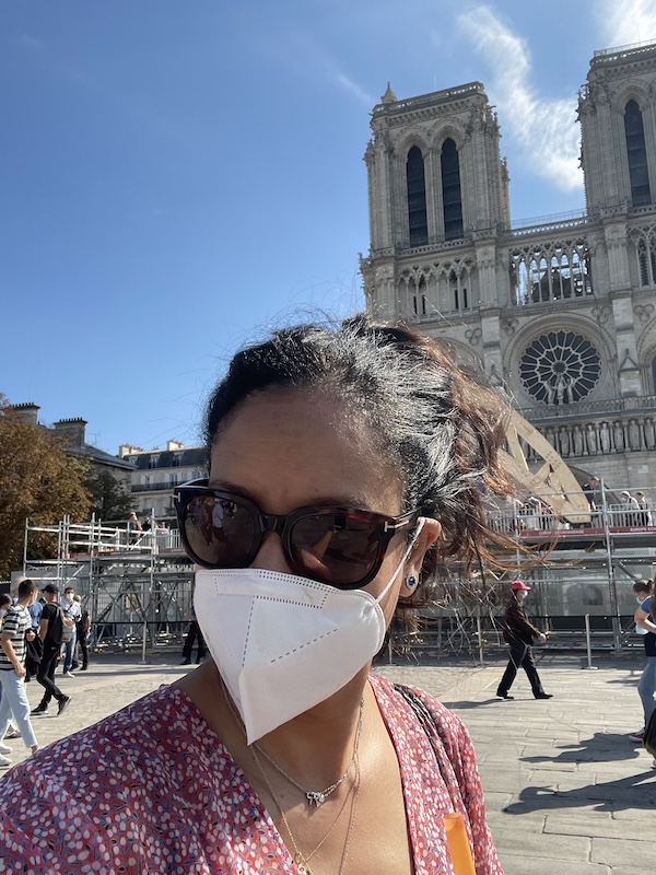 Covid Era, Paris, Notre-Dame. Notice the exterior buttress support behind my hair, as well as the risers for people to see it as construction continued. The square being opened more was a new joy for Parisians.