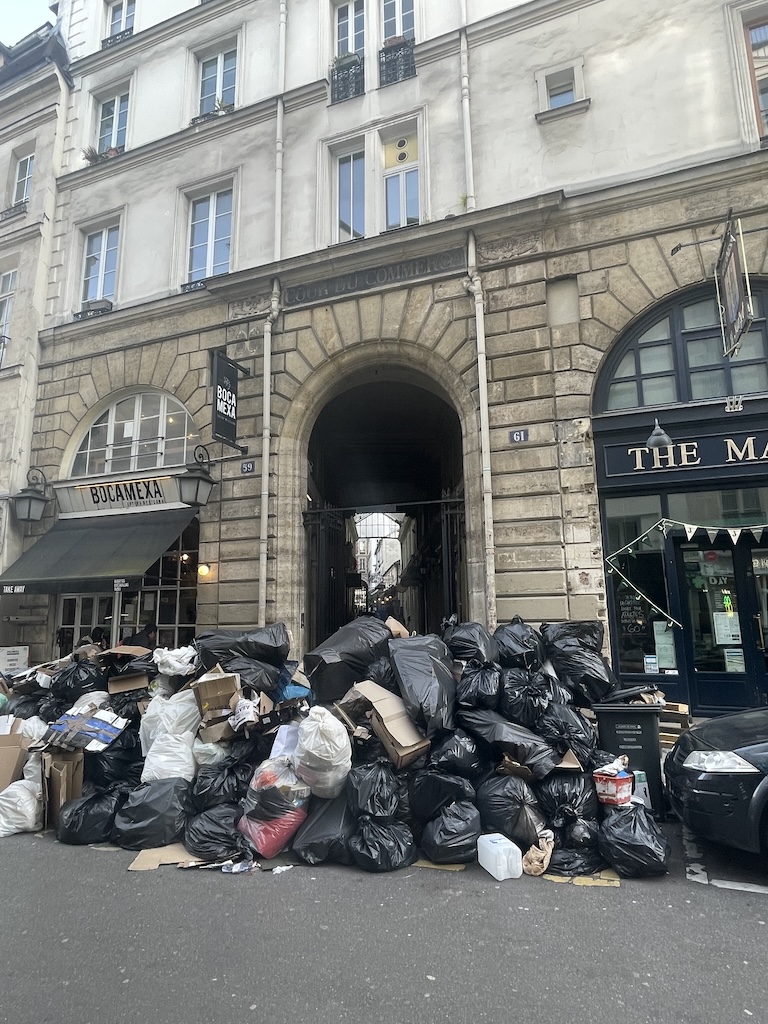 Paris' 6th arrondissement's historic Cour de Commerce, once frequented by Tommy Jefferson, Benjamin Franklin, and Voltaire during the revolution, now covered in trash during 2023 Paris protests. Public protest demands government attention when words, facts, and decency fail.