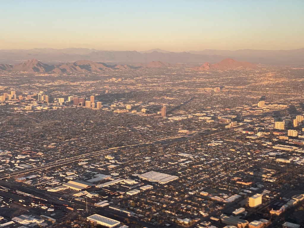 Aerial view of the Phoenix desert landscape from the plane, with sprawling mountains and city below.