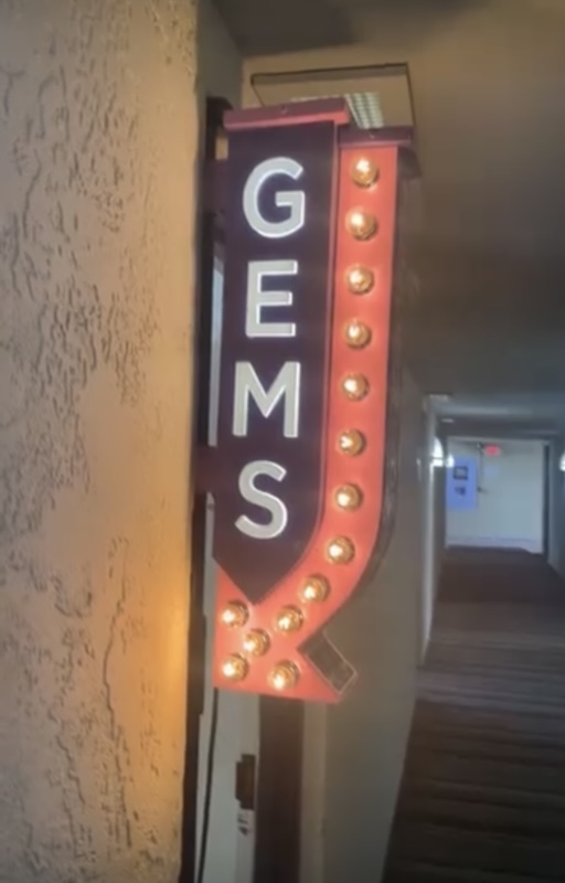 Interior hotel corridor with a “Gems” sign at the Tucson Gem and Mineral Show, illustrating how the event takes over multiple venues across the city.