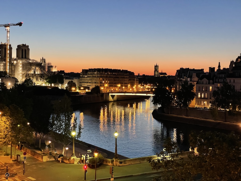 View of Notre Dame and the Seine from Paris Airbnb window, iconic cityscape at golden hour