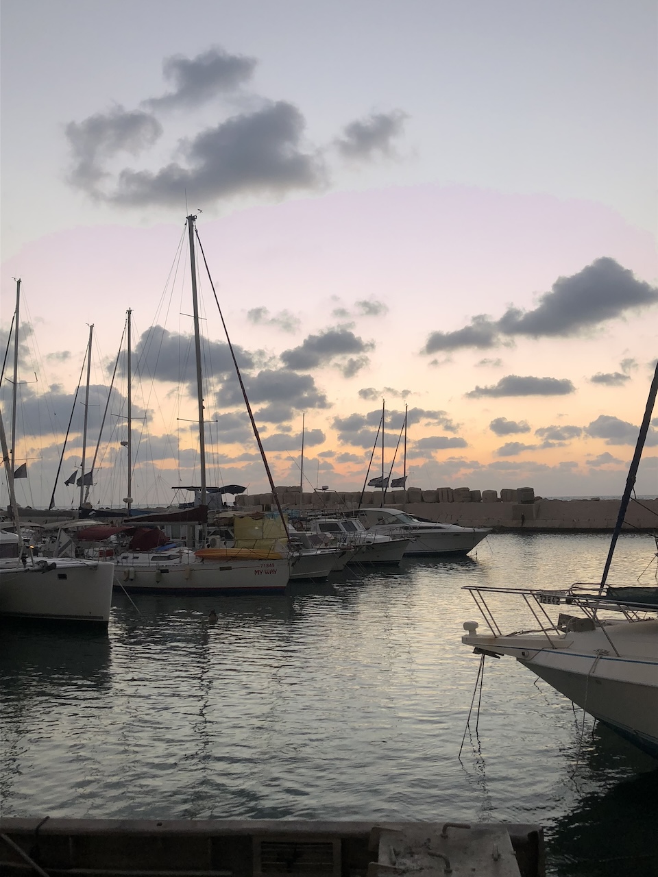 Sailboats drift through the marina in Tel Aviv–Jaffa at sunset, reminding us that Cancer Season asks us to soften, come home to ourselves, and trust the tides carrying us forward. Photo by Leah Gillis, The Diamond Is You (2018).
