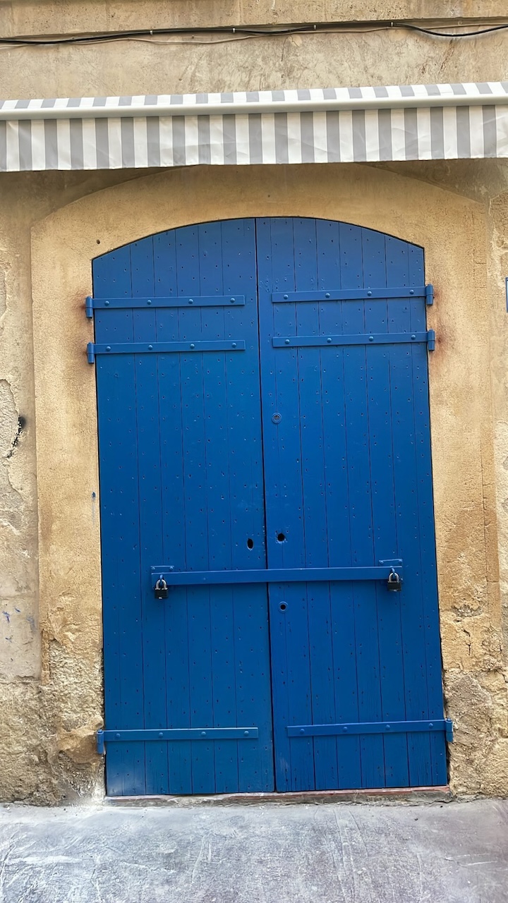 Vintage blue doorway with grey awning in Marseille, France — a closed shop front symbolizing beautiful endings during Virgo season.