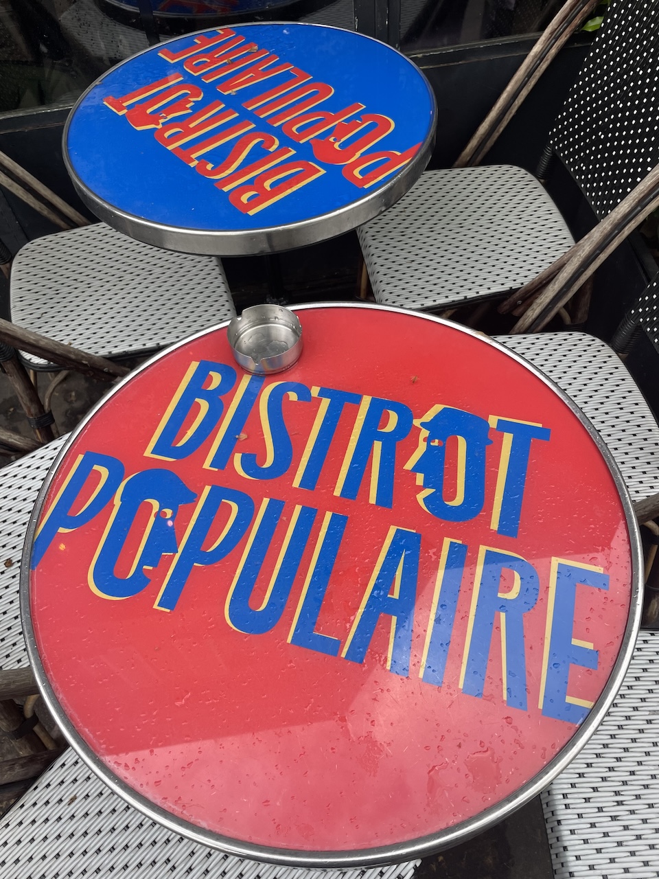 Outdoor bistro tables with 'Bistro Populaire' signage in a Paris neighborhood.